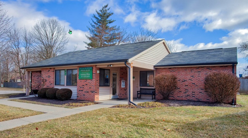 A small brick building with a green sign on the front door.