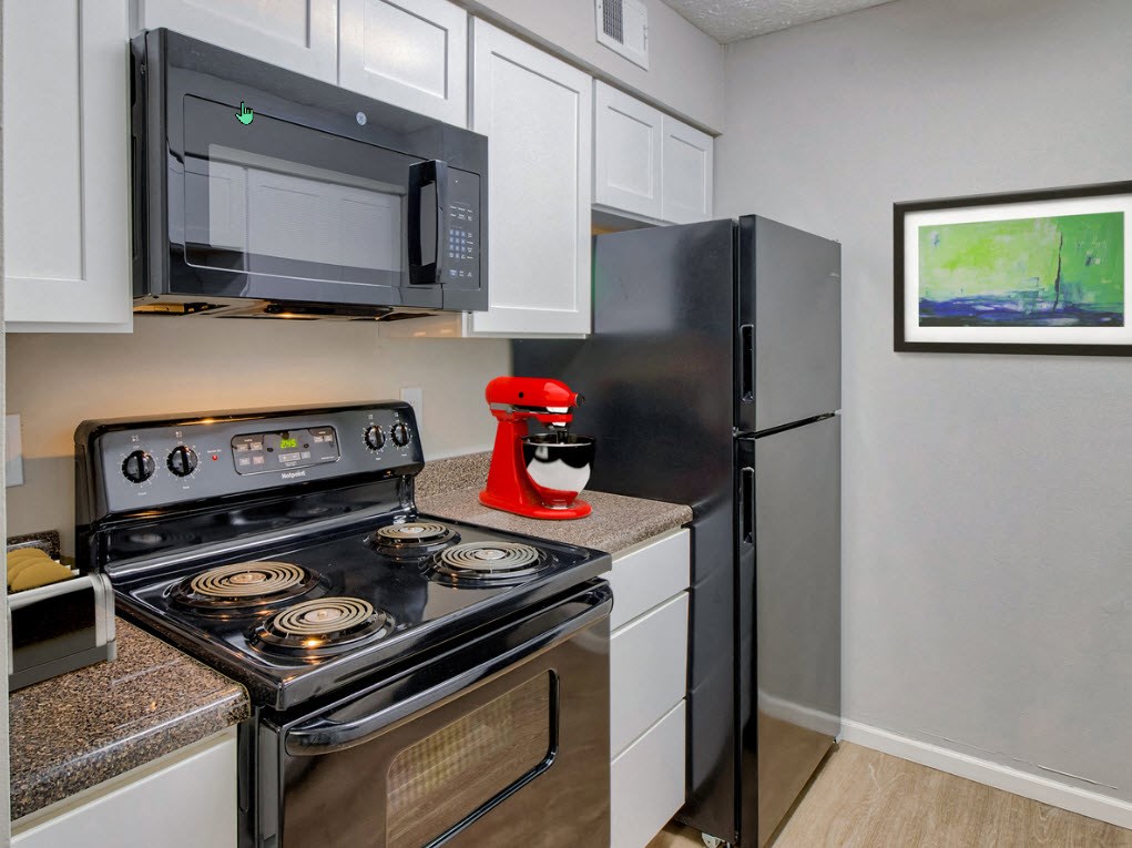 A black microwave is mounted above a black stove in a kitchen.
