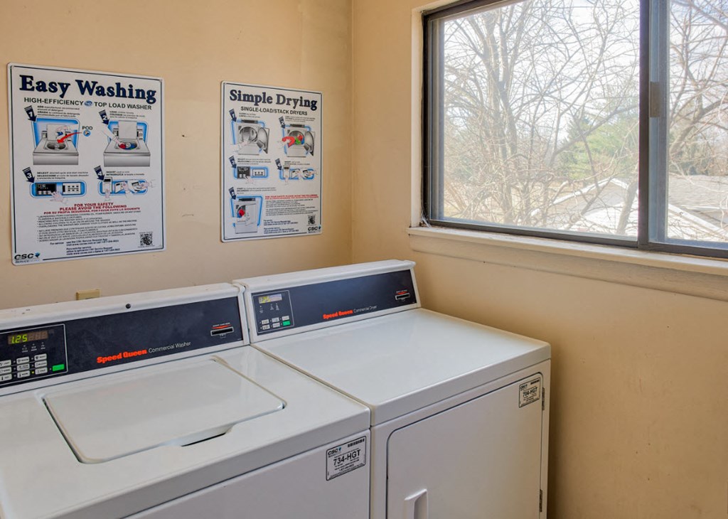A wall of a laundromat with two washing machines and two drying machines.