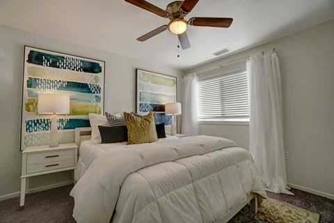 A bedroom with a white bed and a ceiling fan.