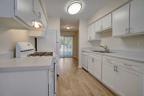 A kitchen with white cabinets and a stove top oven.