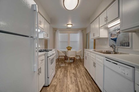 A kitchen with white appliances and wooden floors.