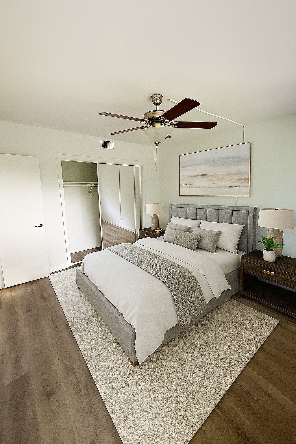A bedroom with a bed, nightstand, and a ceiling fan.