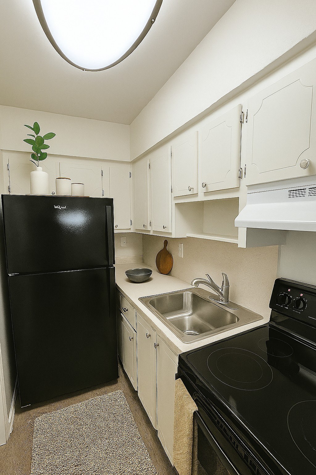A black refrigerator sits next to a sink in a kitchen.