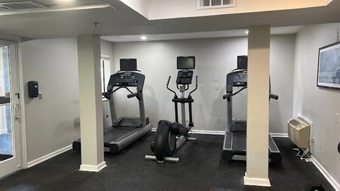 A gym with treadmills, weights, and exercise equipment.