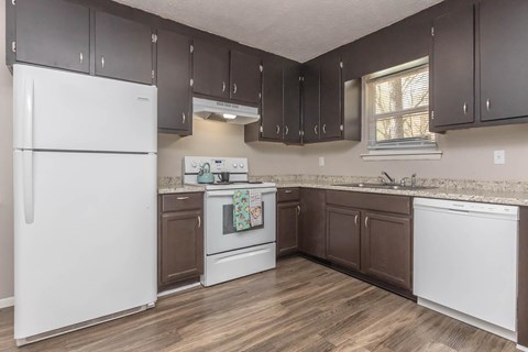 A kitchen with a white refrigerator and brown cabinets.