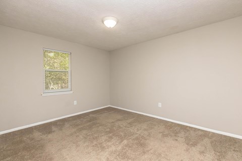 A room with a window and carpeted floor.