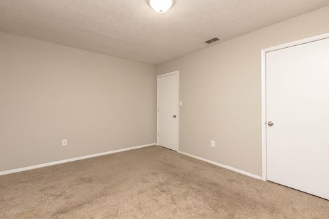 A room with a carpeted floor and two doors.