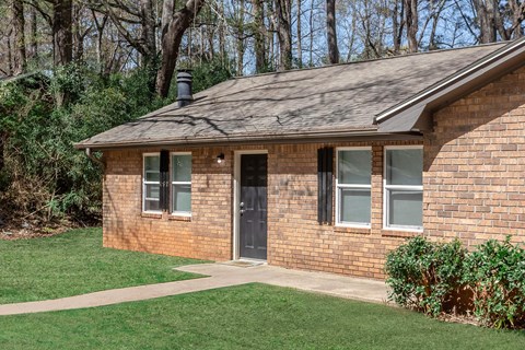 A small brick house with a black door and windows.