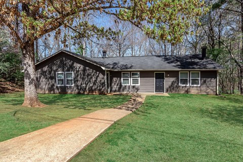 A house with a grey roof and a brown tree in front.
