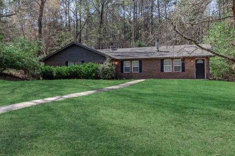 A house with a black roof and a green lawn in front.