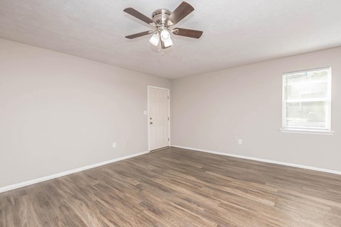 A room with a ceiling fan and wooden flooring.