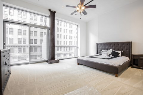 A bedroom with a large bed and a ceiling fan.