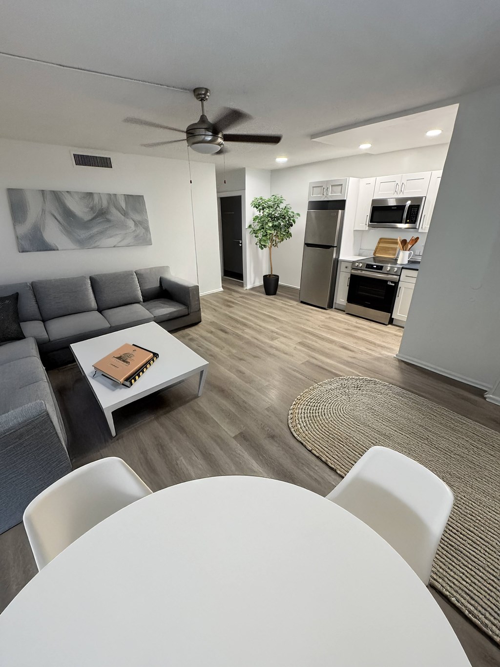 A modern living room with a grey couch, a white coffee table, and a ceiling fan.