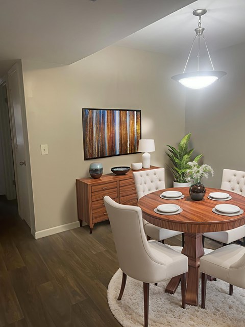 A dining room with a wooden table and white chairs.