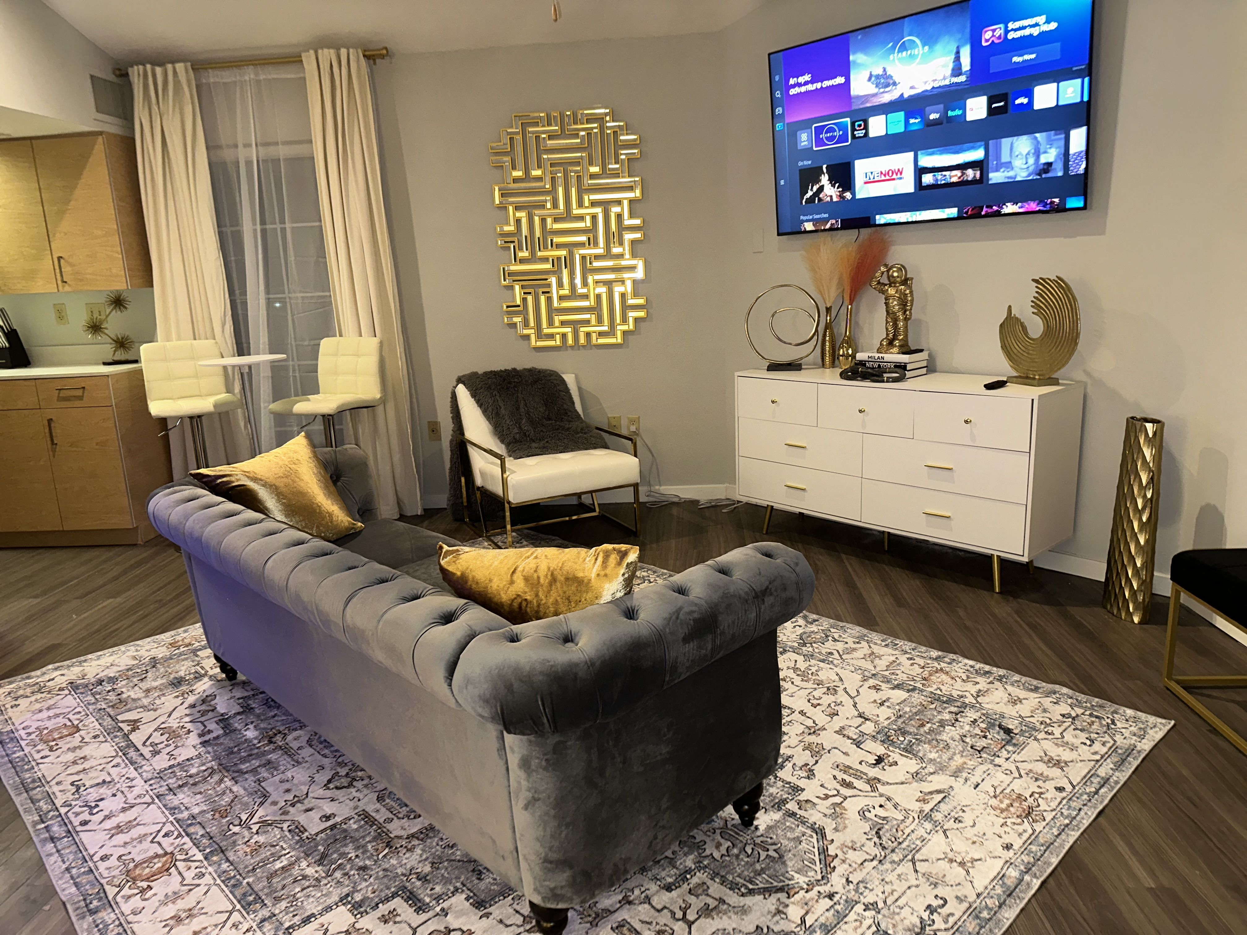 A modern living room with a grey sofa and a flat screen TV mounted on the wall.