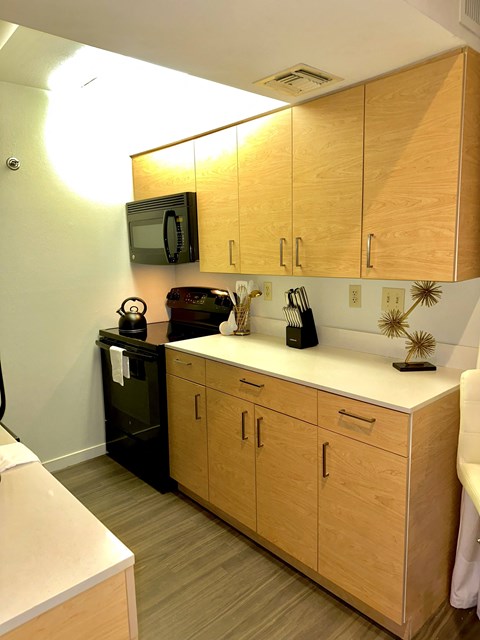 A kitchen with wooden cabinets and a black dishwasher.