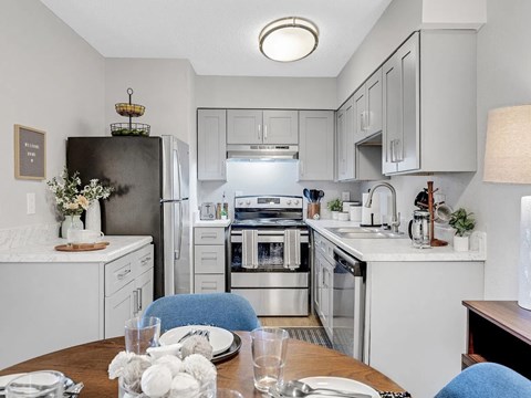 A modern kitchen with a dining table set for two.