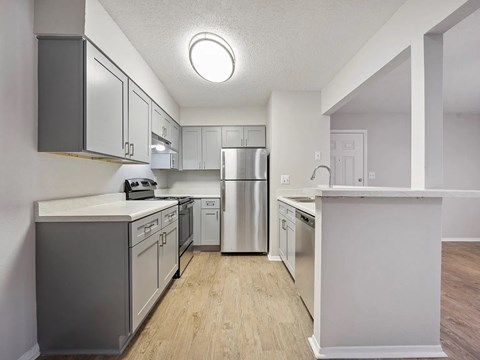 A kitchen with a refrigerator, oven, and sink.