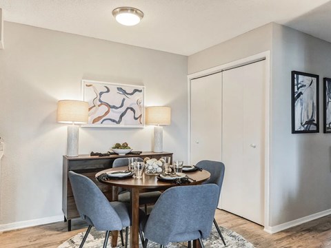A dining room with a table set for two and a painting on the wall.