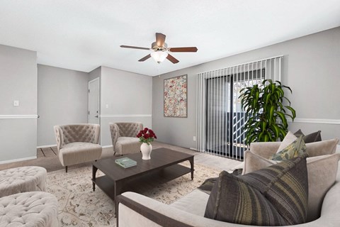 A living room with a couch, chairs, a coffee table, and a potted plant.