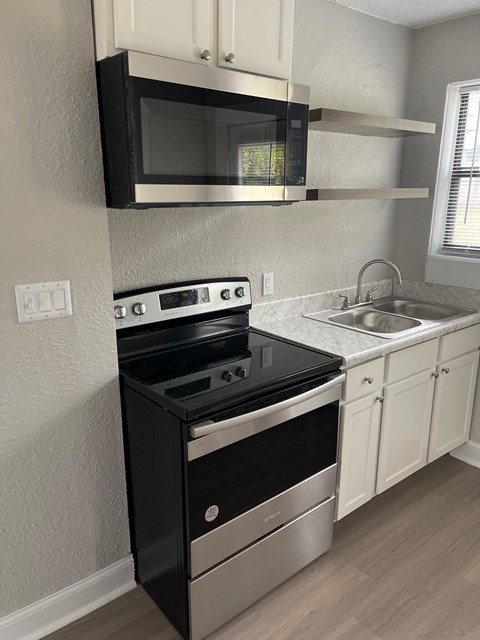 A black stove and microwave in a kitchen.