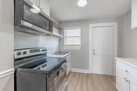 A kitchen with a stove, microwave, and oven.