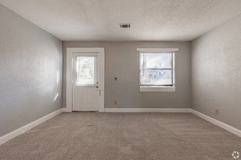 A room with a carpeted floor, a white door, and a window with blinds.