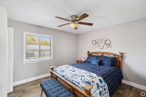 A bedroom with a bed, a ceiling fan, and a window with blinds.