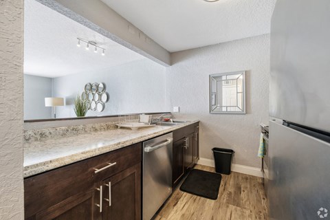 A kitchen with a stainless steel refrigerator and wooden cabinets.