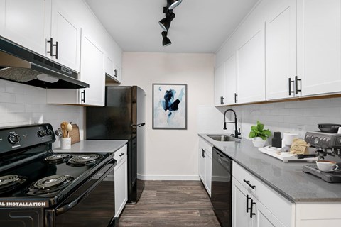 A kitchen with black stove top oven and white cabinets.