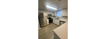 an empty kitchen with white cabinets and stainless steel appliances