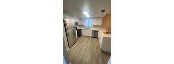 an empty kitchen with white cabinets and a stainless steel refrigerator