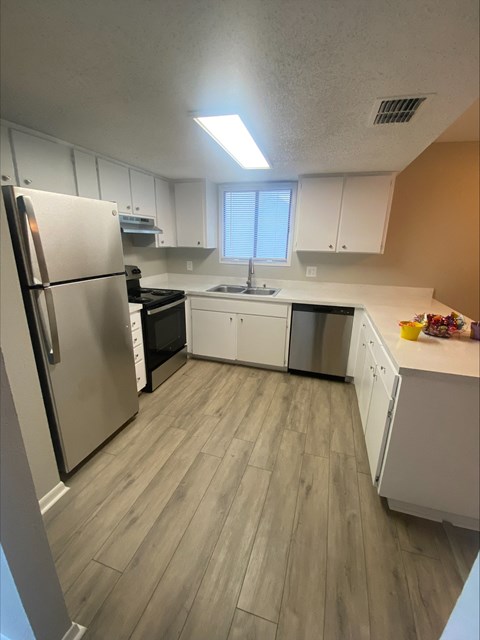 an empty kitchen with white cabinets and a stainless steel refrigerator