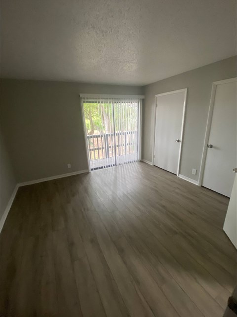 an empty living room with a sliding glass door leading to a balcony