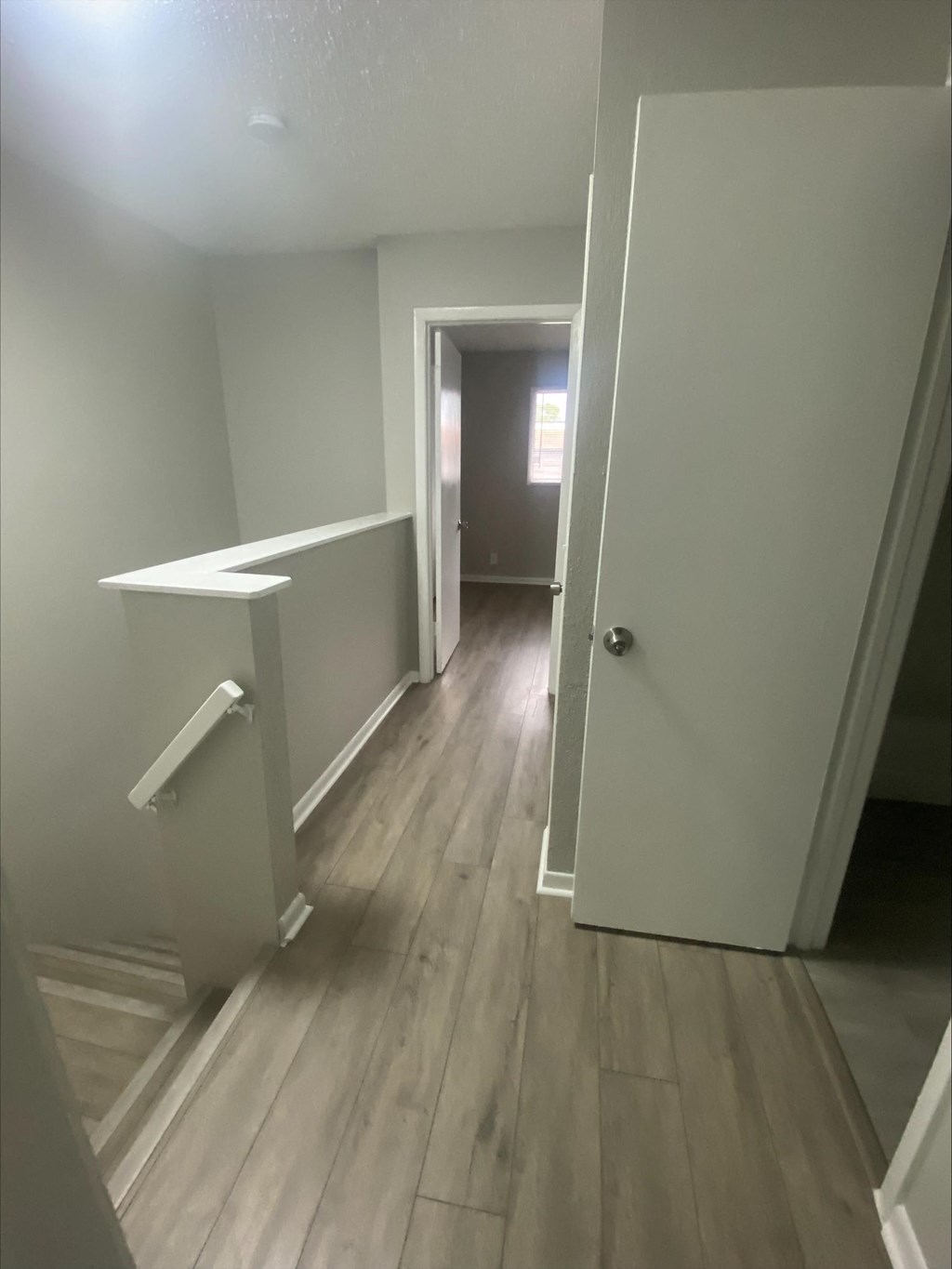 an open door leading into a hallway with hardwood floors and grey walls