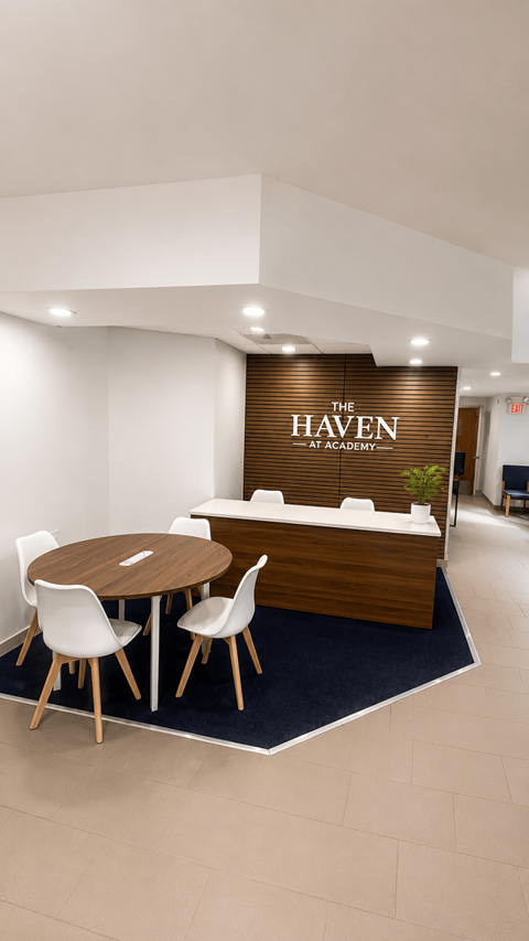 A conference room with a brown table and chairs with a sign that says "The Haven at Apartments".