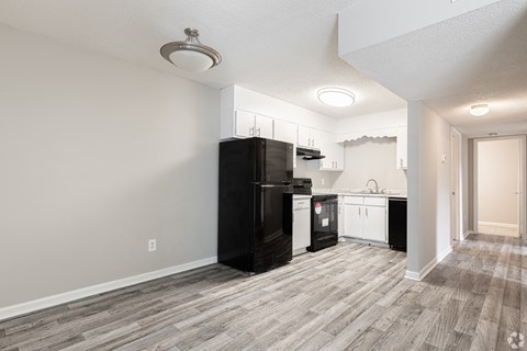A kitchen with black appliances and wooden flooring.