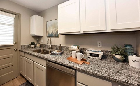 A kitchen with granite countertops and white cabinets.
