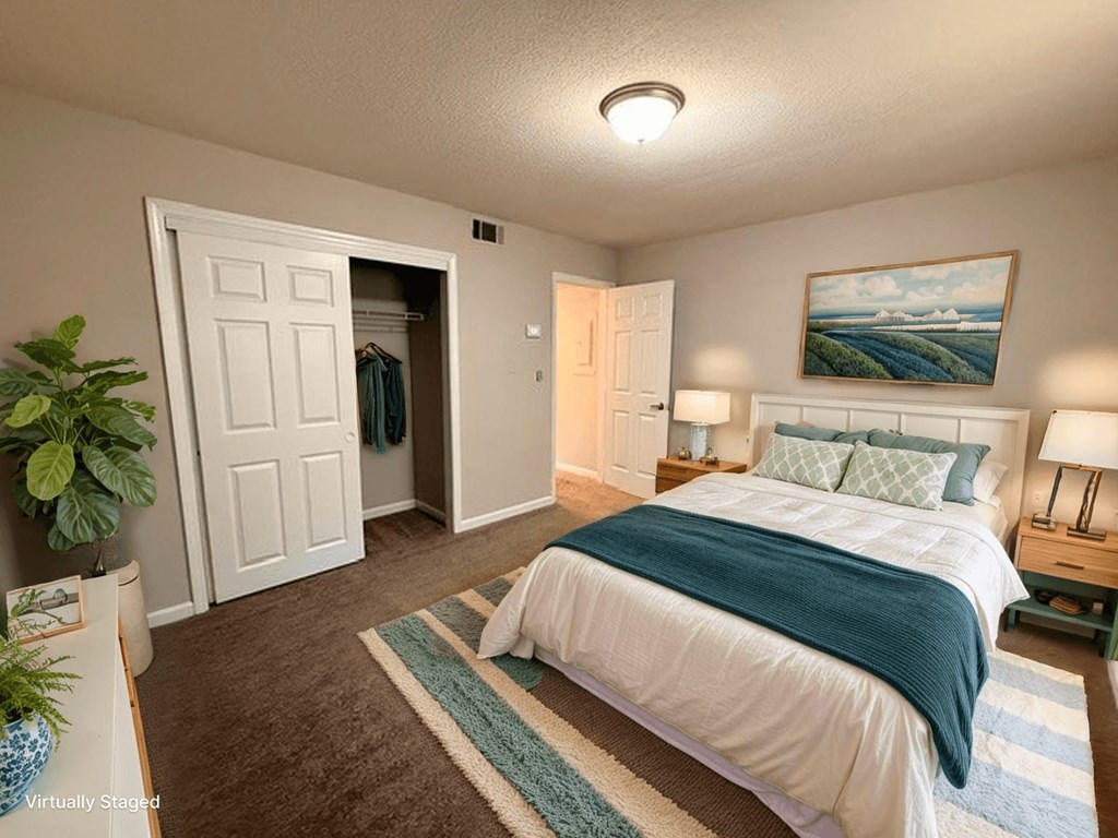 A bedroom with a bed, a plant, and a painting on the wall.