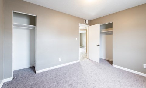 A room with a carpeted floor and two open doors.
