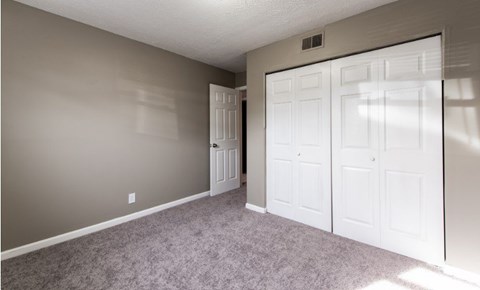 A room with a carpeted floor and white doors.