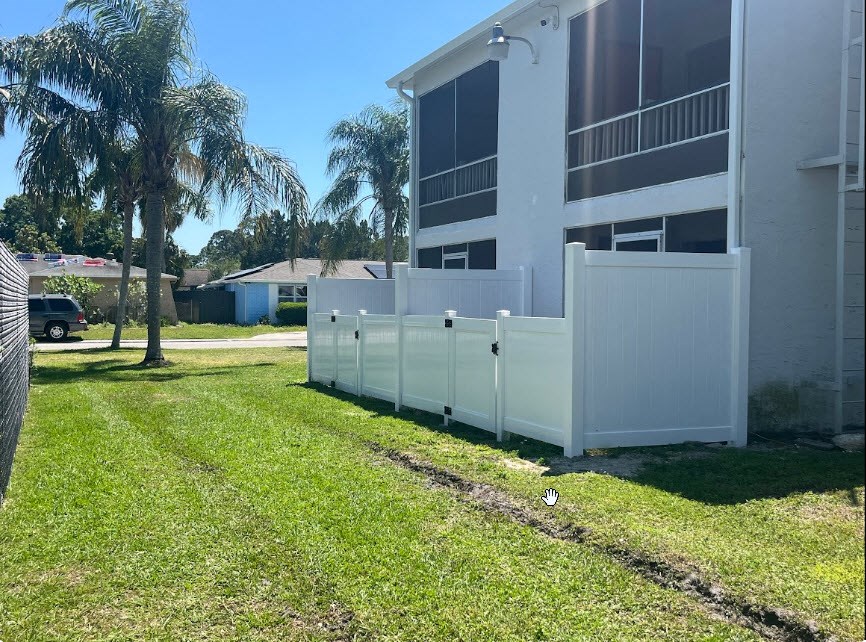 a white fence in front of a house with palm trees