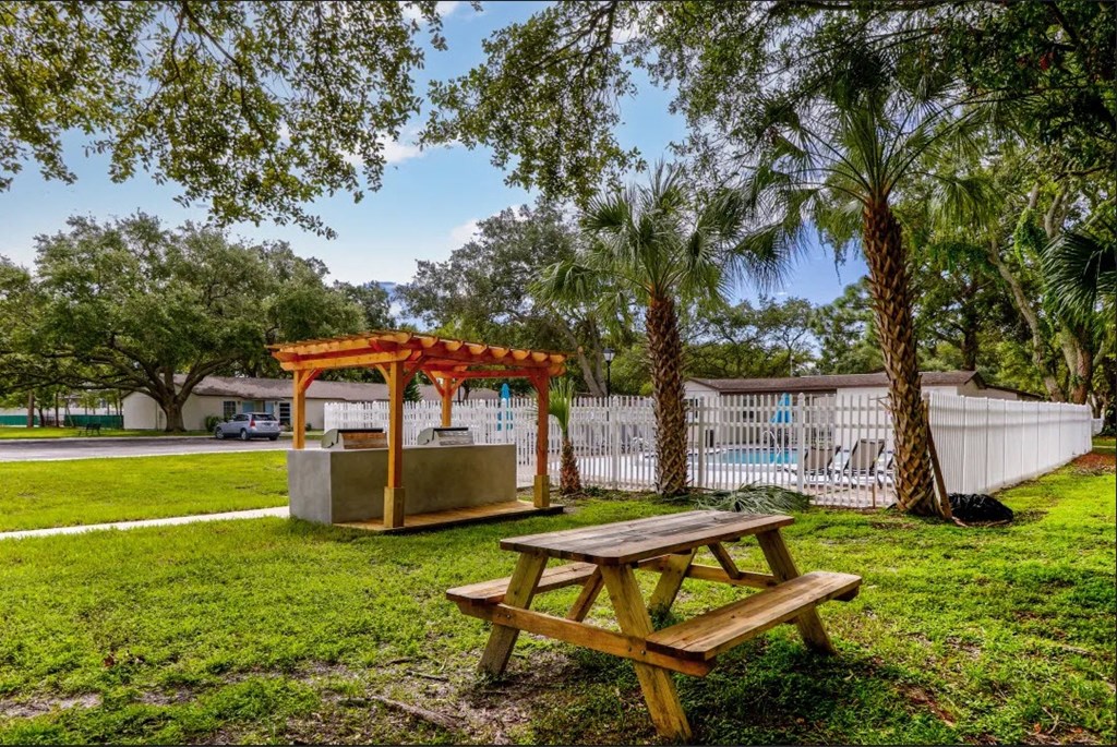 a picnic table with a gazebo and a pool in the background