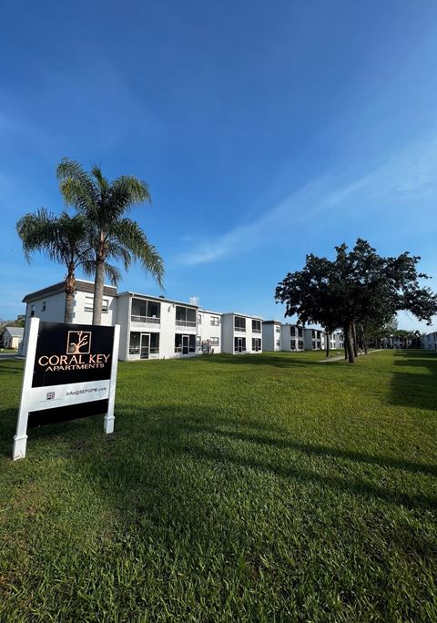 a building with palm trees and a sign in the grass