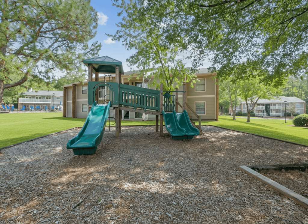 A playground with a green slide and a wooden structure.
