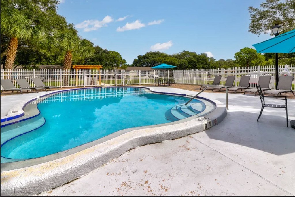 a resort style pool with chaise lounge chairs and umbrellas