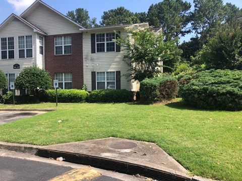 A brick and siding apartment building with a green lawn in front.