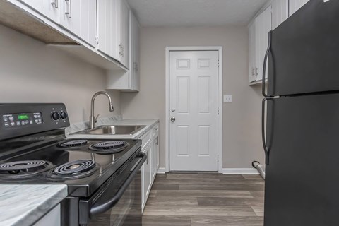 A kitchen with a black stove top oven and a black refrigerator.