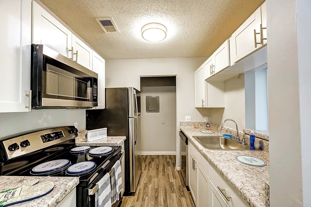 A kitchen with a black stove top oven and a black microwave above it A kitchen with a black stove top oven and a black microwave above it at Sedgefield Square Apartments, North Carolina, 27407